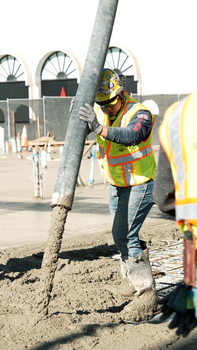 Worker guiding a concrete pump hose during a pour